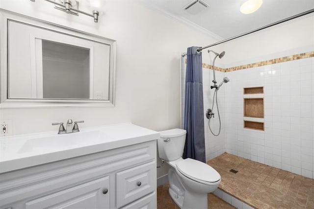 bathroom featuring toilet, vanity, visible vents, ornamental molding, and tiled shower