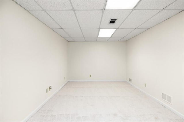 empty room featuring a paneled ceiling, baseboards, light carpet, and visible vents