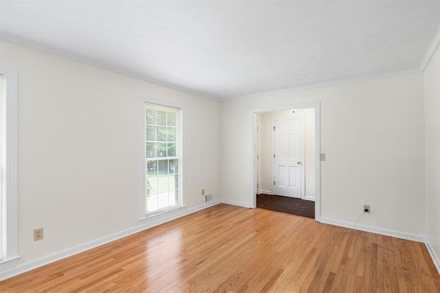 unfurnished room with ornamental molding, light wood finished floors, and baseboards