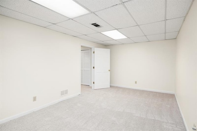 unfurnished room with light colored carpet, visible vents, a paneled ceiling, and baseboards