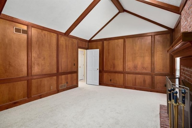 unfurnished living room featuring lofted ceiling with beams, visible vents, a decorative wall, and carpet flooring