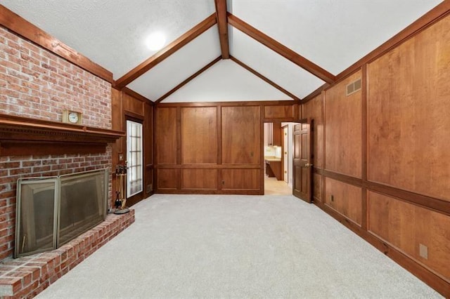 unfurnished living room featuring wooden walls, visible vents, light colored carpet, vaulted ceiling with beams, and a brick fireplace