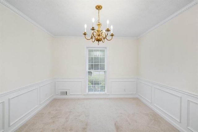 spare room featuring a chandelier, a decorative wall, light colored carpet, visible vents, and crown molding