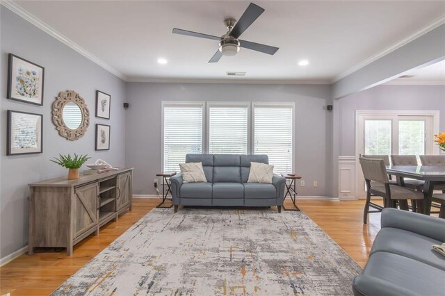 living room featuring ornamental molding, light hardwood / wood-style flooring, and ceiling fan