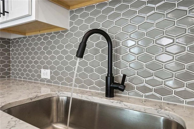 details with a sink, light stone countertops, and white cabinetry