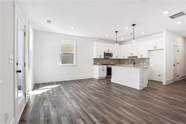 kitchen featuring tasteful backsplash, white cabinetry, stainless steel appliances, and dark wood-style flooring