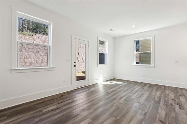 unfurnished room featuring visible vents, wood finished floors, and baseboards