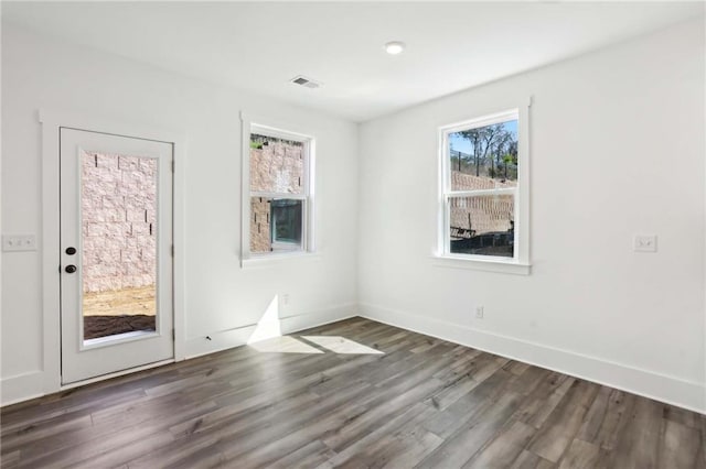 spare room featuring visible vents, baseboards, and wood finished floors