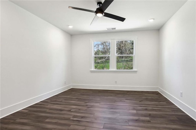 spare room with visible vents, baseboards, dark wood-style floors, and a ceiling fan