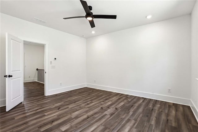 spare room with dark wood-style floors, visible vents, ceiling fan, and baseboards