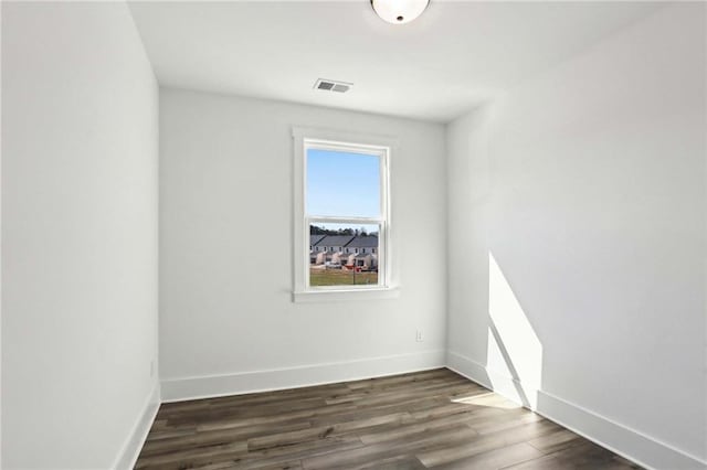 unfurnished room with visible vents, baseboards, and dark wood-style flooring