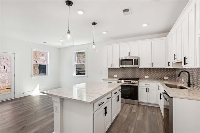 kitchen with dark wood-style floors, visible vents, a sink, decorative backsplash, and stainless steel appliances