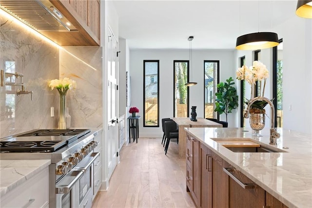 kitchen with pendant lighting, sink, backsplash, appliances with stainless steel finishes, and light wood-type flooring