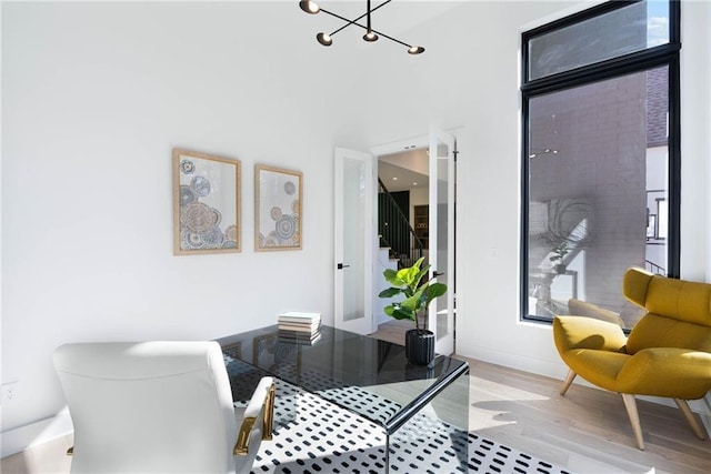 office area featuring a notable chandelier, light hardwood / wood-style flooring, and a high ceiling