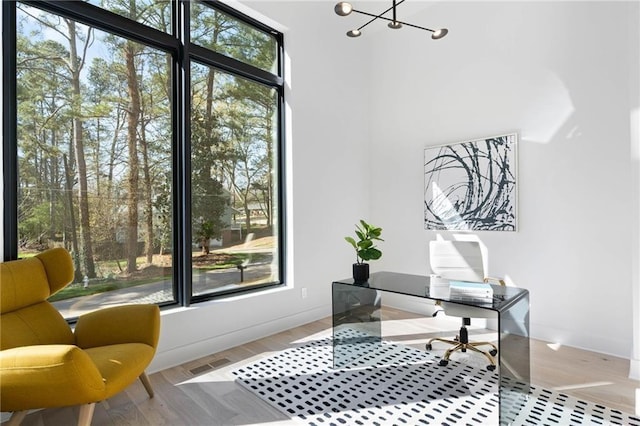 office featuring a high ceiling, a healthy amount of sunlight, and light hardwood / wood-style flooring