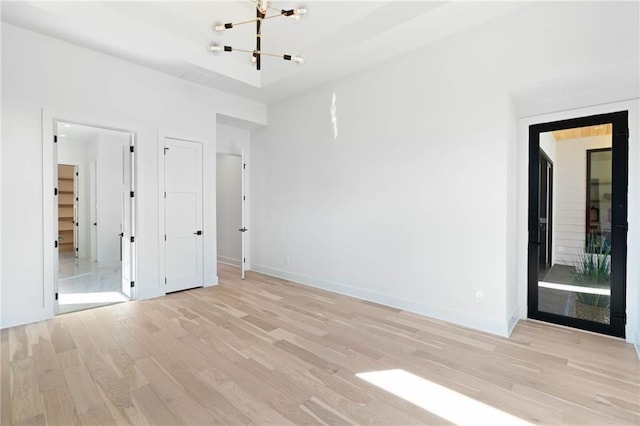 unfurnished bedroom featuring light hardwood / wood-style floors, a chandelier, and ensuite bath