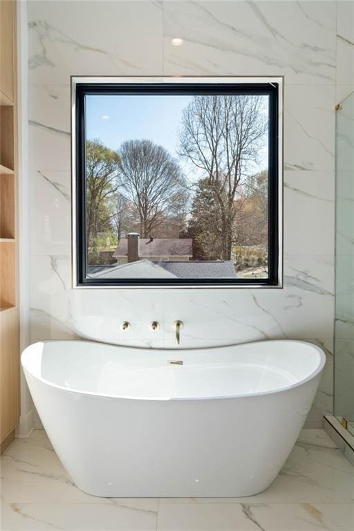 bathroom with a bathing tub, tile walls, and a wealth of natural light