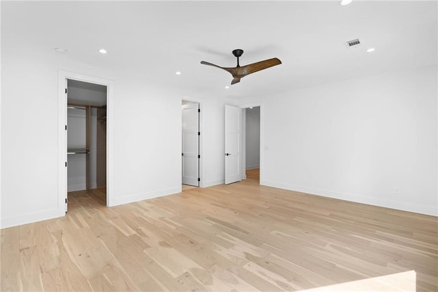 unfurnished bedroom featuring ceiling fan, light wood-type flooring, a closet, and a spacious closet