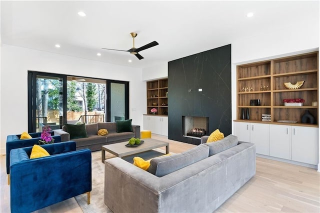 living room featuring a fireplace, ceiling fan, and light hardwood / wood-style floors