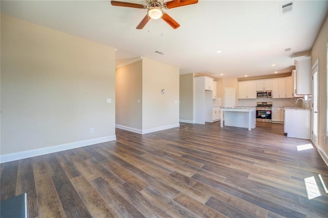 unfurnished living room with dark hardwood / wood-style floors, ceiling fan, and sink