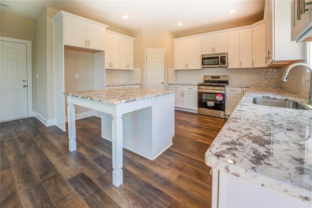 kitchen featuring stainless steel appliances, sink, a center island, dark hardwood / wood-style floors, and white cabinetry