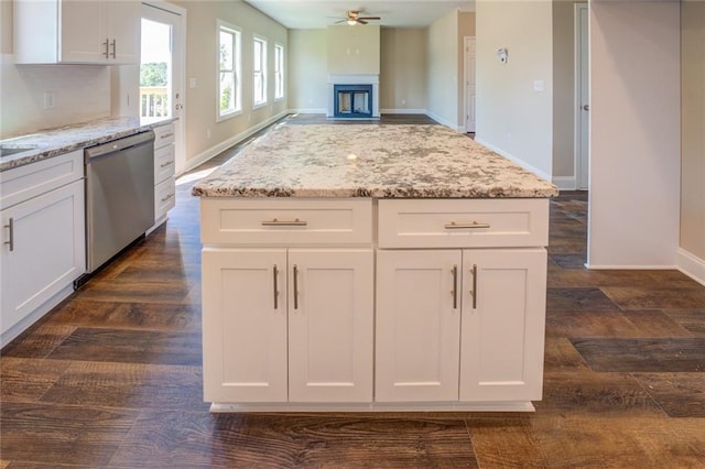 kitchen with stainless steel dishwasher, light stone countertops, and white cabinetry