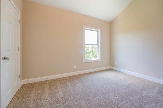 carpeted spare room with lofted ceiling