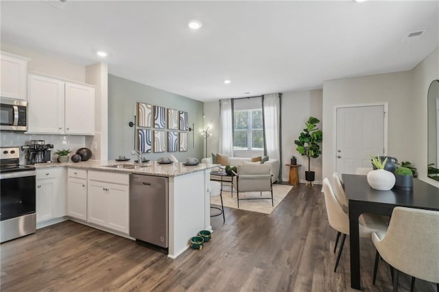 kitchen featuring dark wood-type flooring, sink, appliances with stainless steel finishes, light stone countertops, and white cabinets