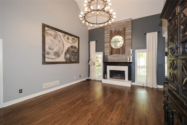 204 Maple Creek Chase, Woodstock, GA 30188 - unfurnished living room featuring visible vents, an inviting chandelier, a brick fireplace, dark wood finished floors, and a towering ceiling