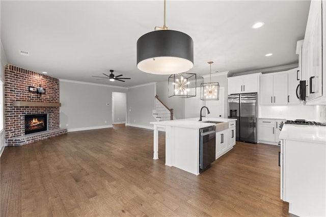 kitchen featuring ornamental molding, a ceiling fan, a sink, open floor plan, and appliances with stainless steel finishes