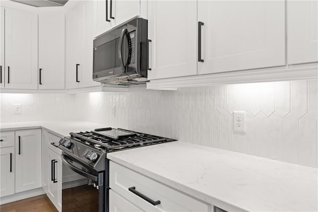 kitchen with white cabinetry, black appliances, light stone counters, and backsplash