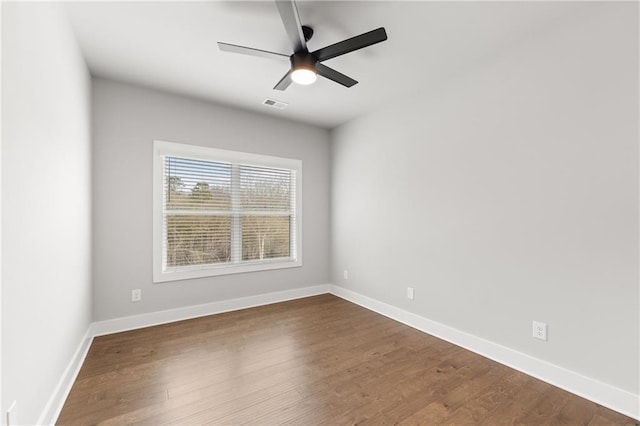 spare room with dark wood finished floors, visible vents, and baseboards