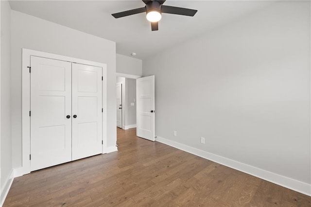 unfurnished bedroom with a closet, ceiling fan, baseboards, and wood finished floors