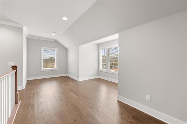 bonus room with dark wood-type flooring, a healthy amount of sunlight, baseboards, and vaulted ceiling