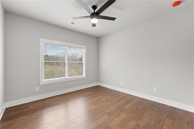 unfurnished room featuring dark wood-style floors, visible vents, a ceiling fan, and baseboards