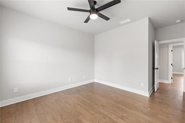 spare room featuring visible vents, baseboards, ceiling fan, and wood finished floors