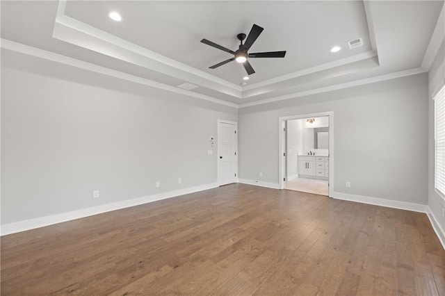 unfurnished bedroom featuring visible vents, ornamental molding, dark wood-style floors, baseboards, and a raised ceiling