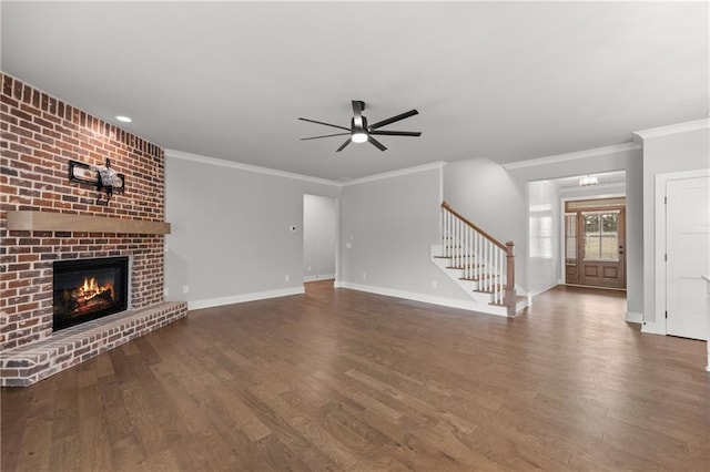 unfurnished living room featuring stairs, a brick fireplace, wood finished floors, and ceiling fan