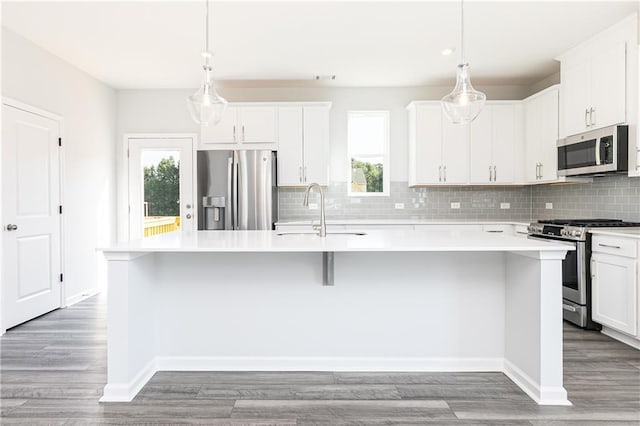 kitchen with pendant lighting, a center island with sink, sink, white cabinetry, and stainless steel appliances