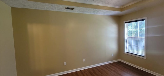 unfurnished room with a textured ceiling, visible vents, dark wood-style flooring, crown molding, and baseboards