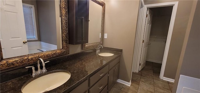 bathroom with baseboards, double vanity, and a sink