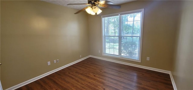 empty room featuring baseboards, ceiling fan, and dark wood-style floors