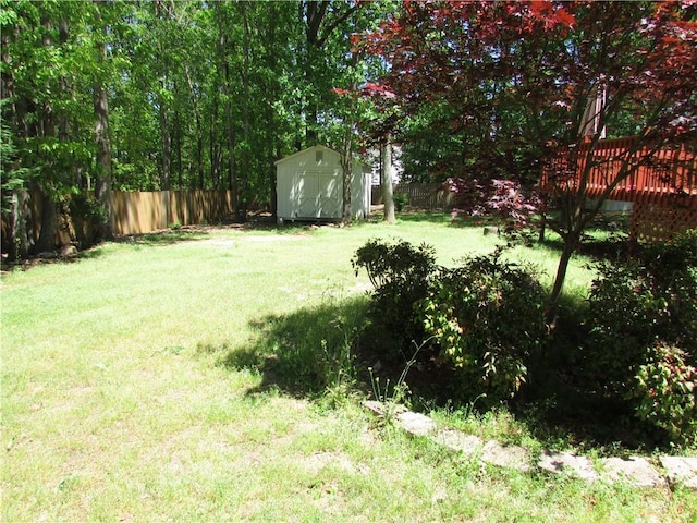 view of yard with a fenced backyard, a shed, and an outbuilding