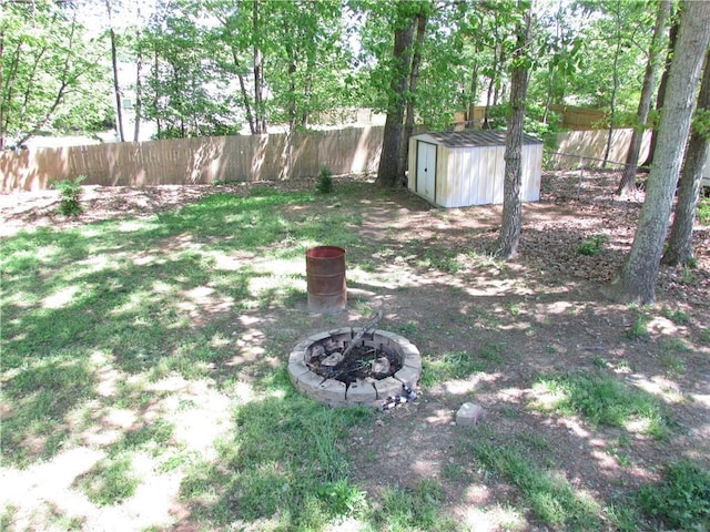 view of yard featuring an outdoor fire pit, a fenced backyard, an outbuilding, and a storage shed