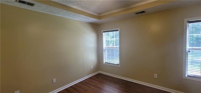 empty room with crown molding, visible vents, baseboards, and dark wood-style floors