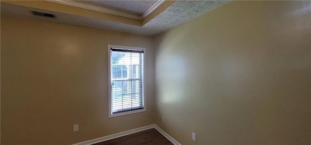 empty room featuring visible vents, baseboards, ornamental molding, and dark wood-style floors