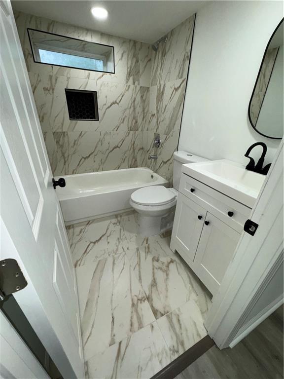 full bathroom with tiled shower / bath, vanity, and toilet