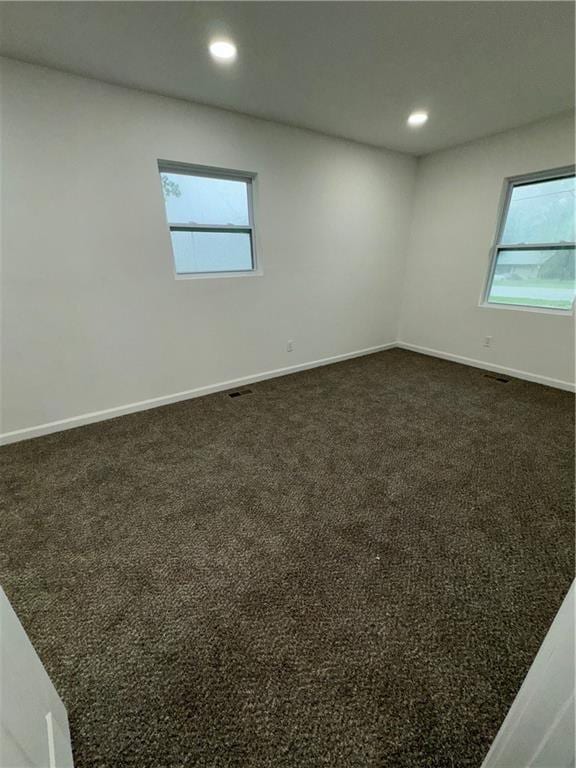 empty room with a wealth of natural light and dark carpet