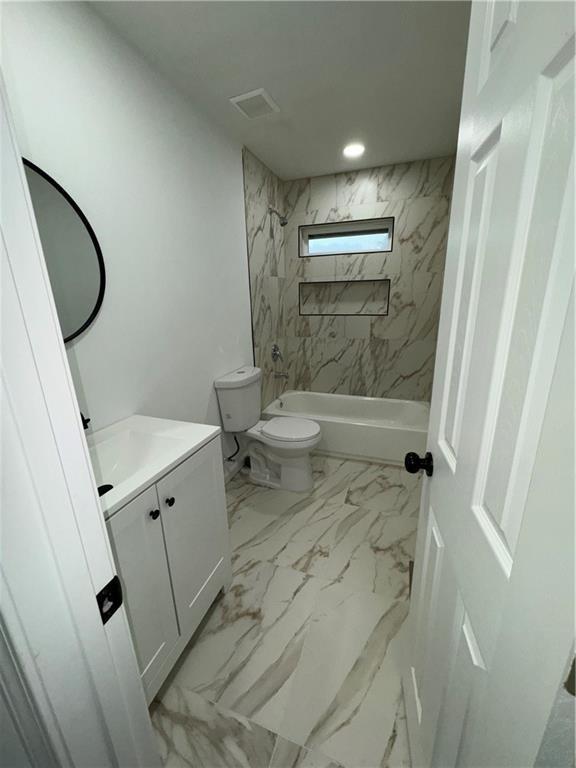 full bathroom featuring tiled shower / bath combo, vanity, and toilet