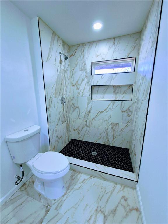 bathroom featuring toilet and tiled shower